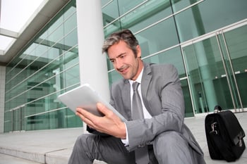 Businessman using electronic tablet in front of offices building