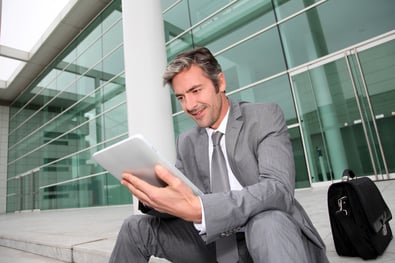 Businessman using electronic tablet in front of offices building