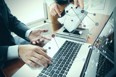 business documents on office table with smart phone and digital tablet and stylus and two colleagues discussing data in the background business documents on office table with smart phone and digital tablet and stylus and two colleagues discussing data in the background